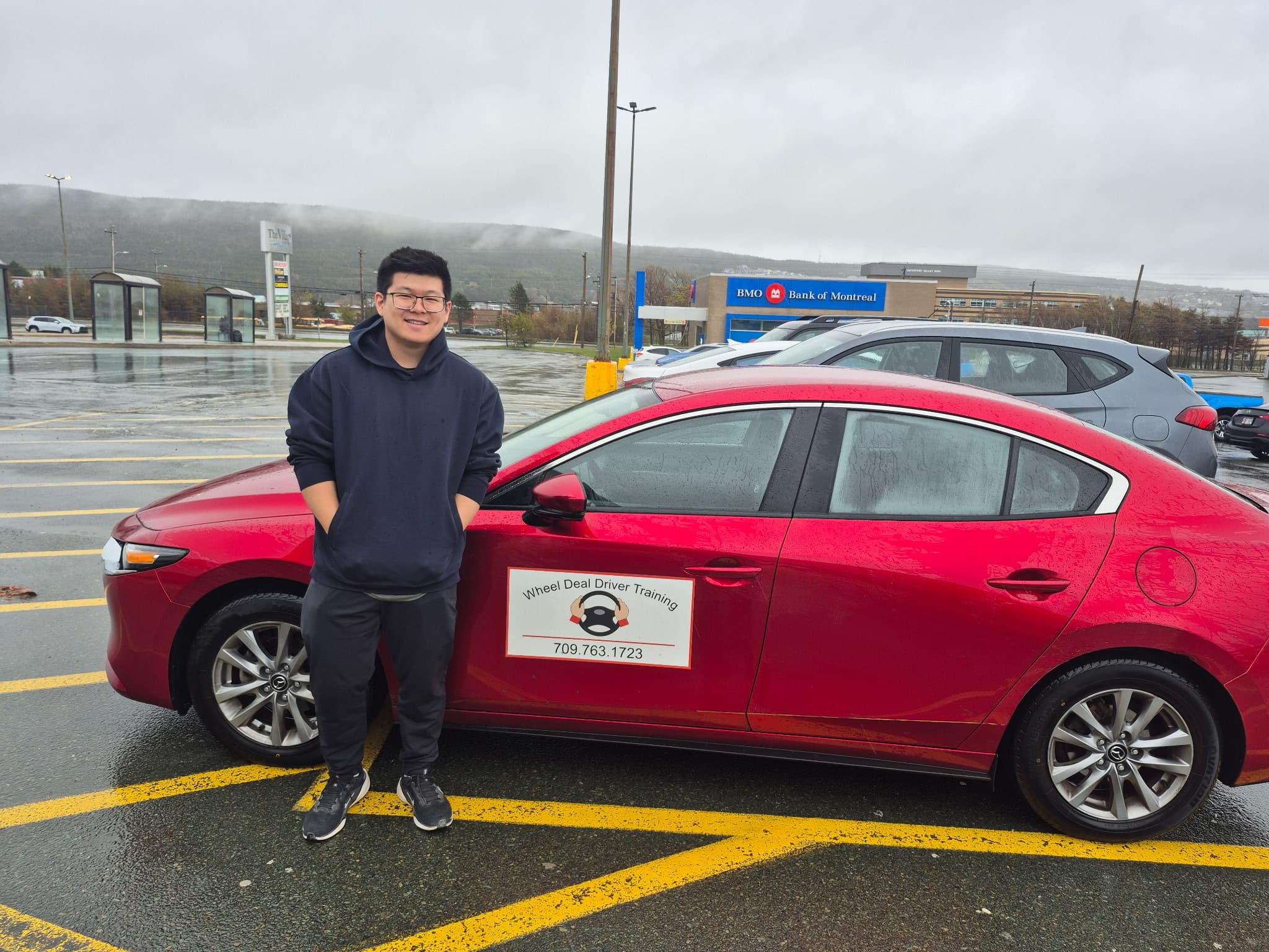 A Wheel Deal student standing proudly next to the training vehicle